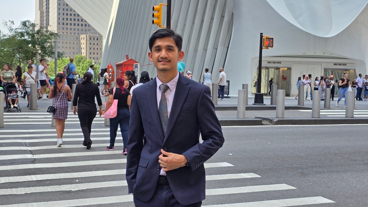 Bimal Kumal in a navy suit on a crosswalk in front of the Oculus in Lower Manhattan